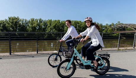 Zwei Personen auf Fahrrädern die an einem Fluss entlang fahren