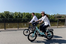 Zwei Personen auf Fahrrädern die an einem Fluss entlang fahren